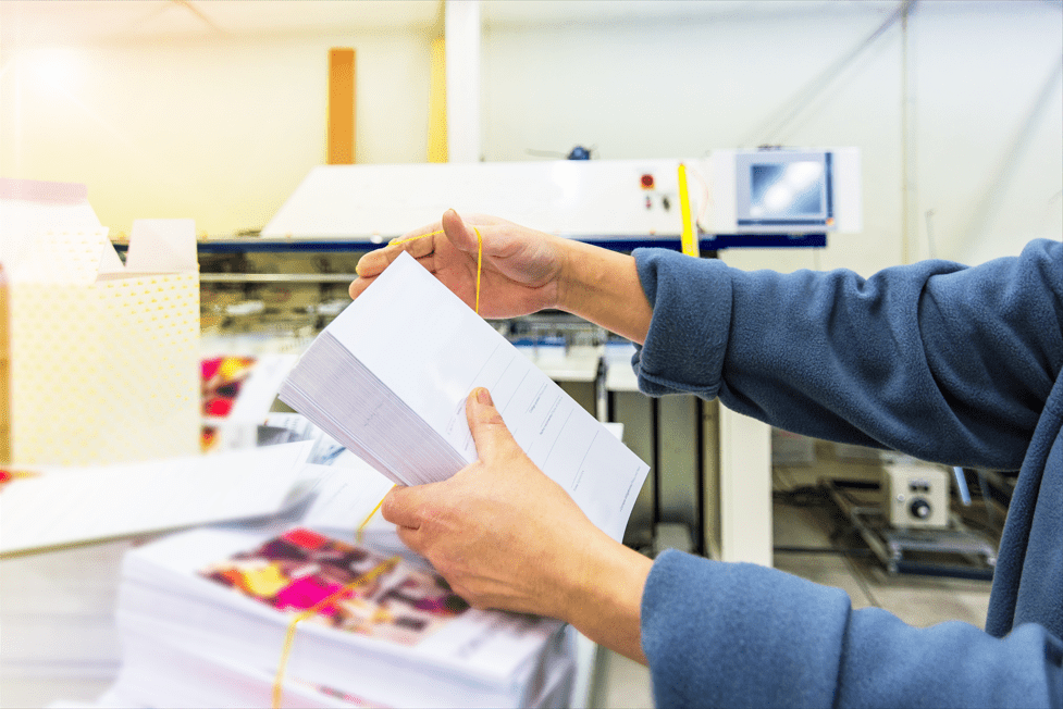 Worker folding leaflets in a digital printing workshop at Low Cost Printing, demonstrating affordable and efficient printing services.